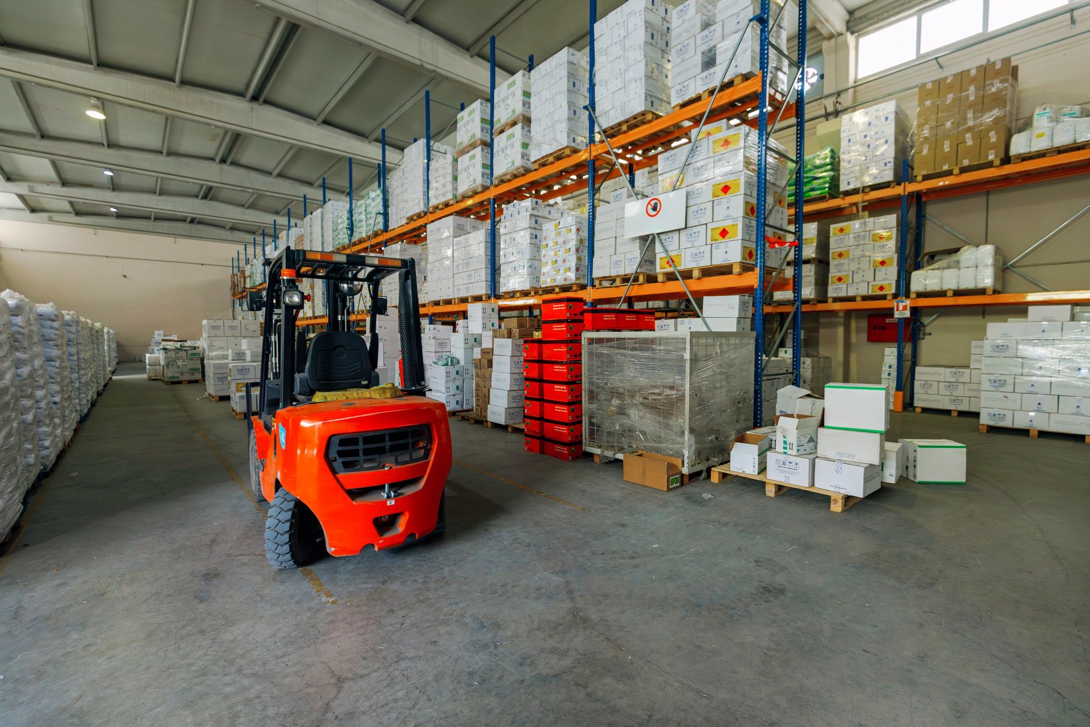 Forklift operating in a warehouse aisle with stacked goods